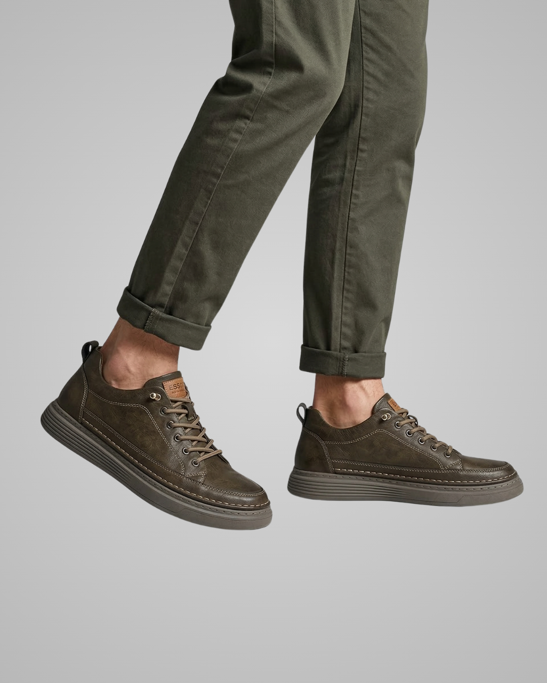 Brown suede shoes worn with green pants on a gray background