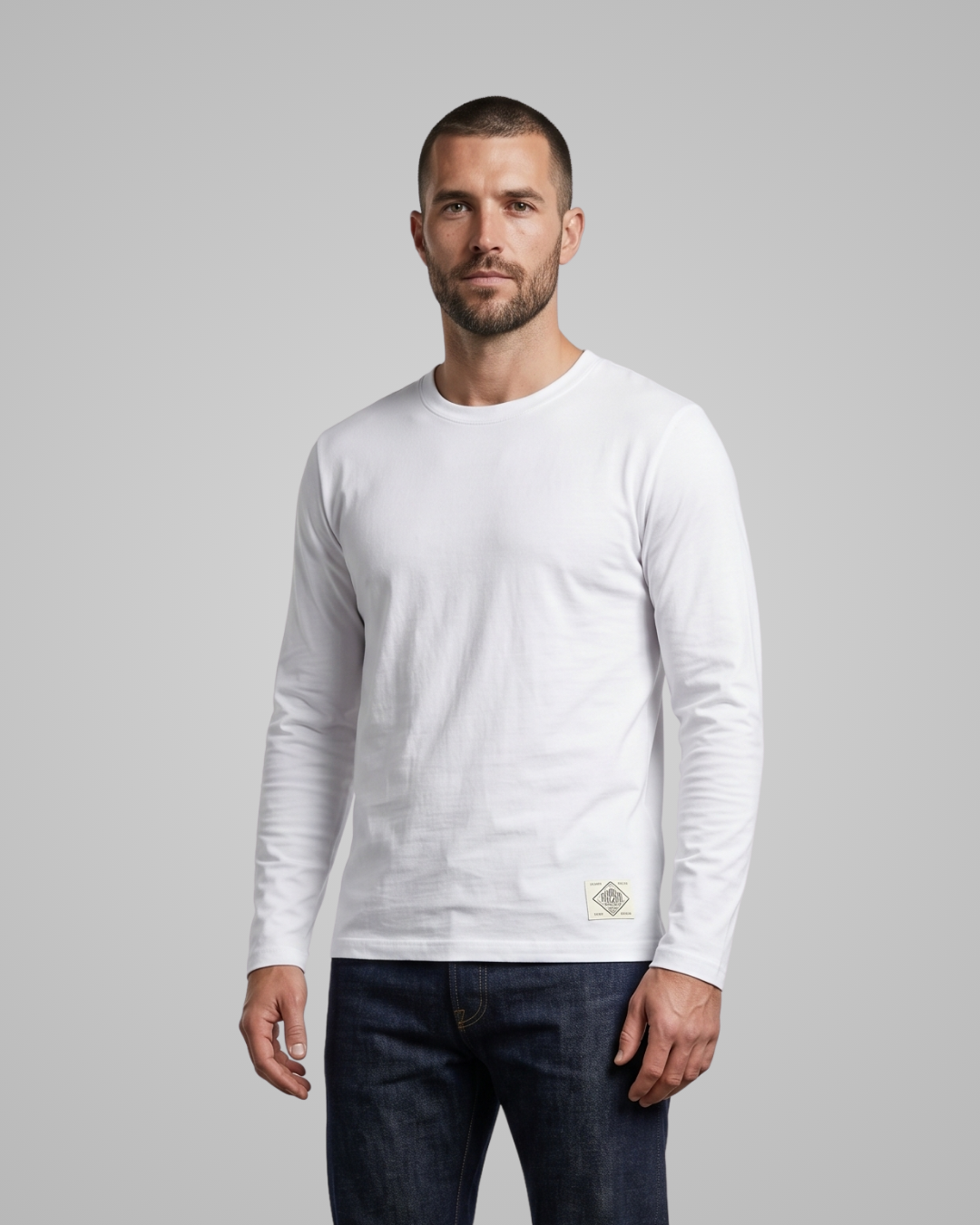 Man wearing a white long-sleeve shirt with a small logo on a gray background