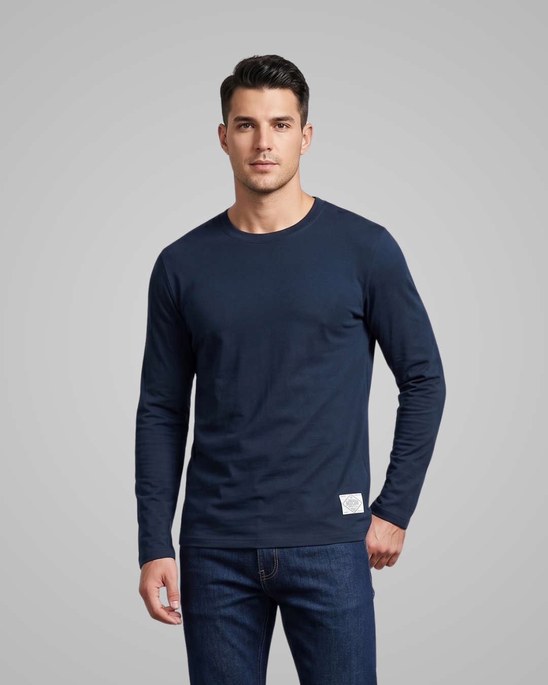 Man wearing a navy long-sleeve shirt and jeans on a gray background