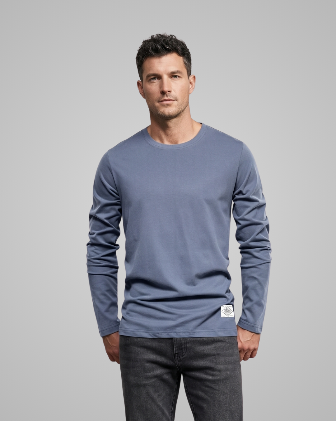 Man wearing a blue long-sleeve shirt with a logo on a gray background