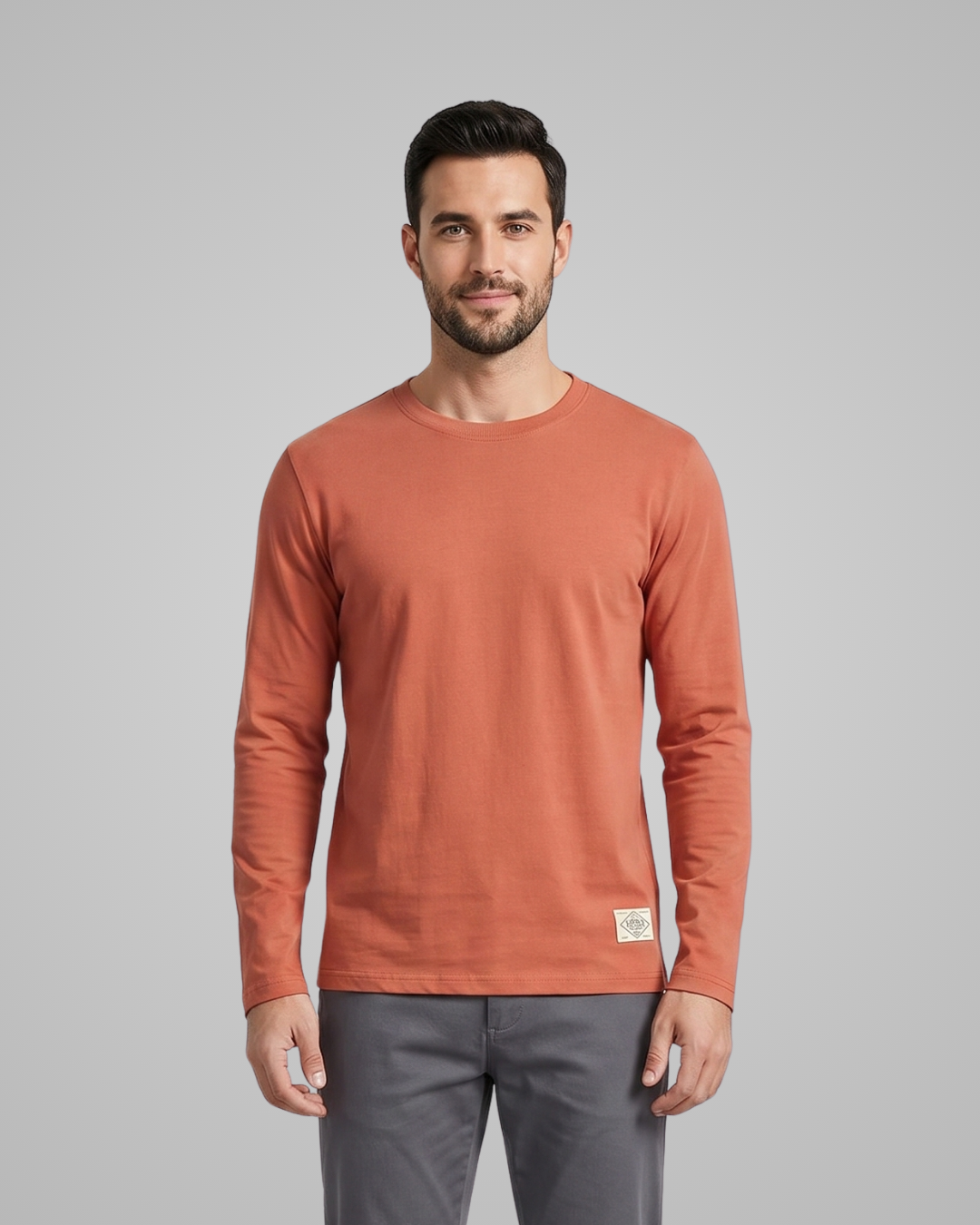 Man wearing a rust-colored long-sleeve shirt on a gray background
