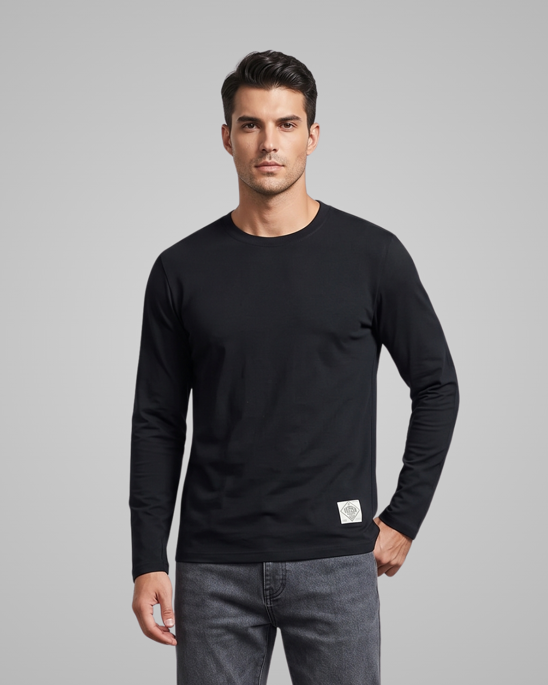 Man wearing a black long-sleeve shirt with a small white label on a gray background