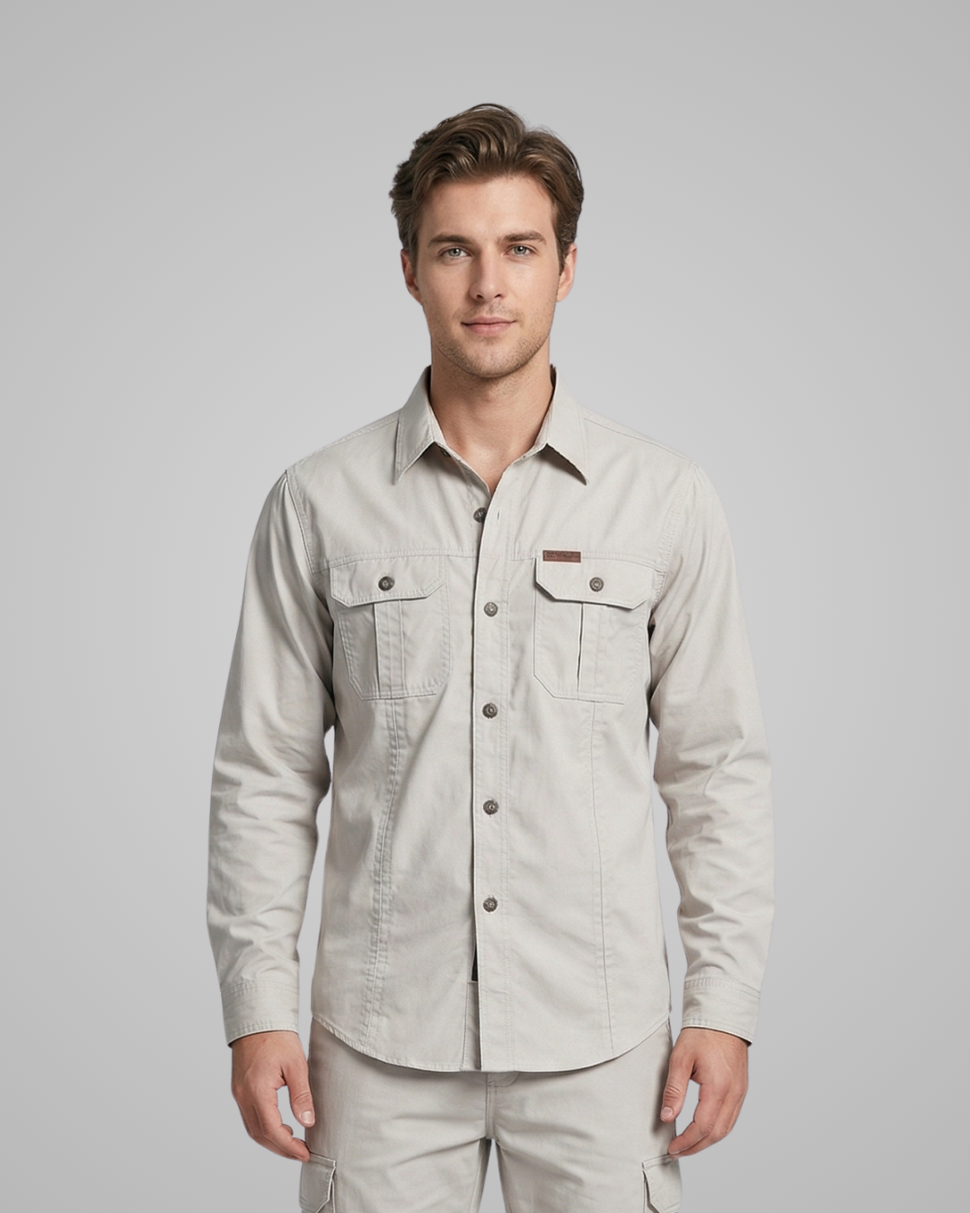 Man wearing a light beige button-up shirt against a gray background
