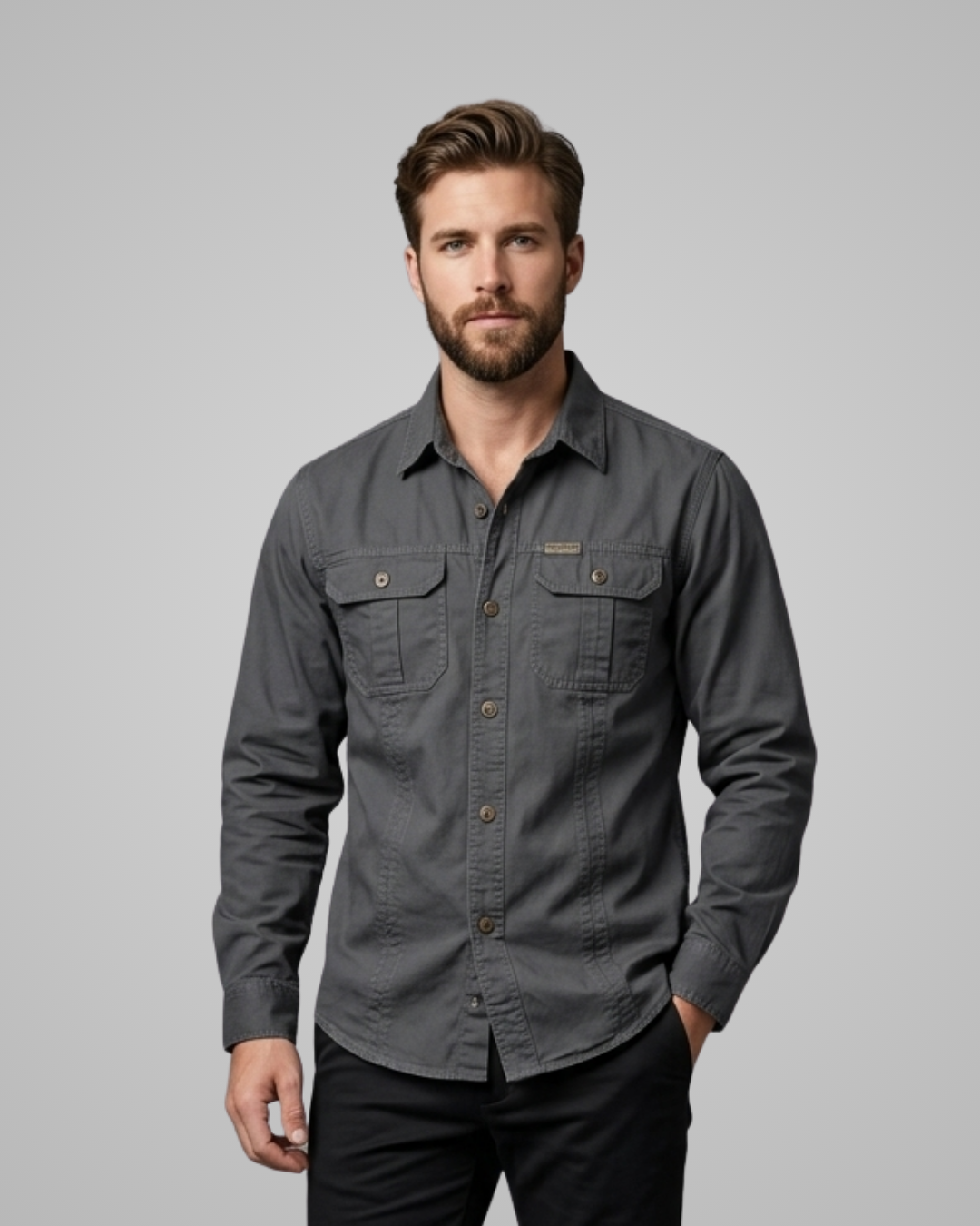 Man wearing a gray button-up shirt against a plain background