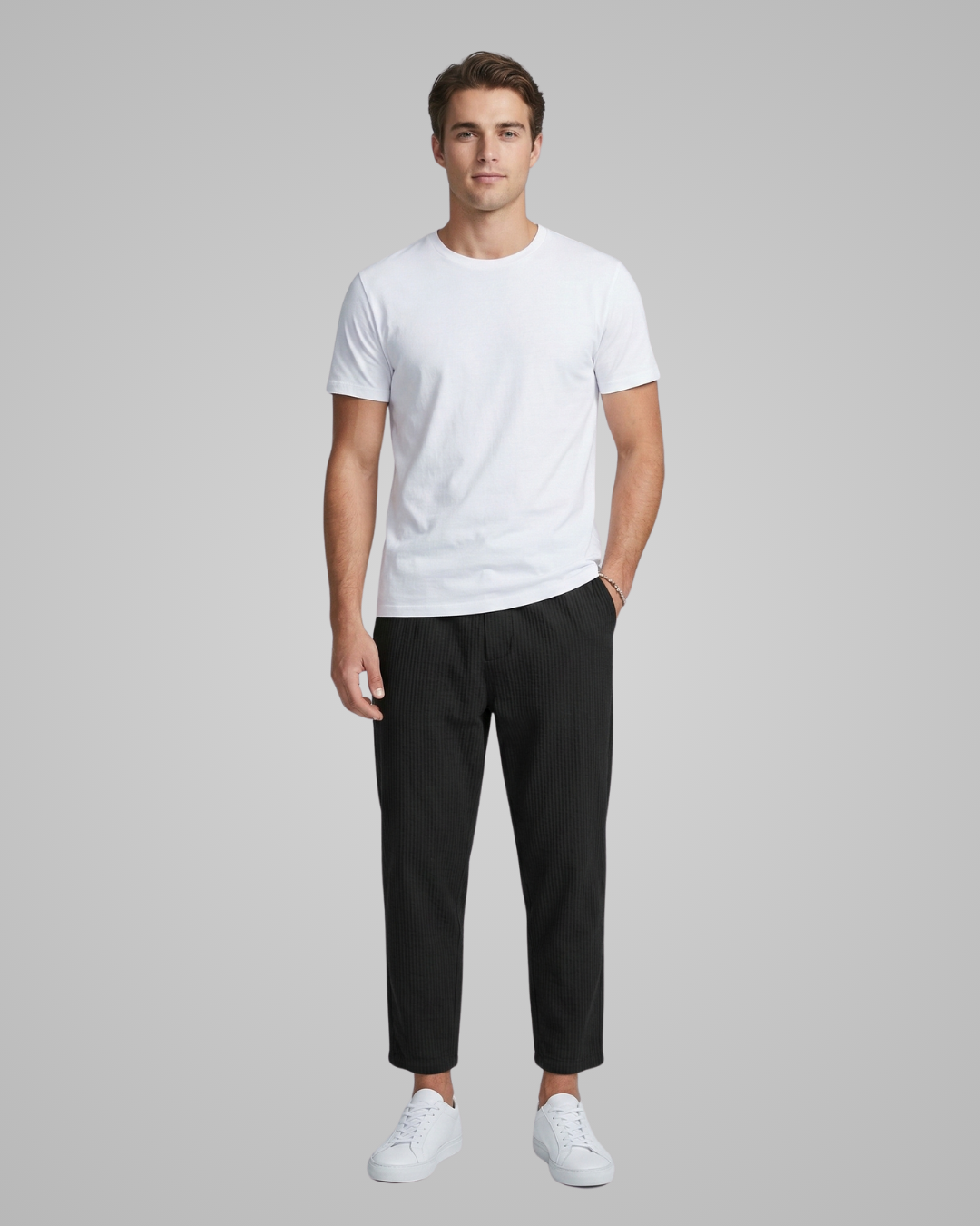 Man wearing a white t-shirt, black pants, and white sneakers on a gray background