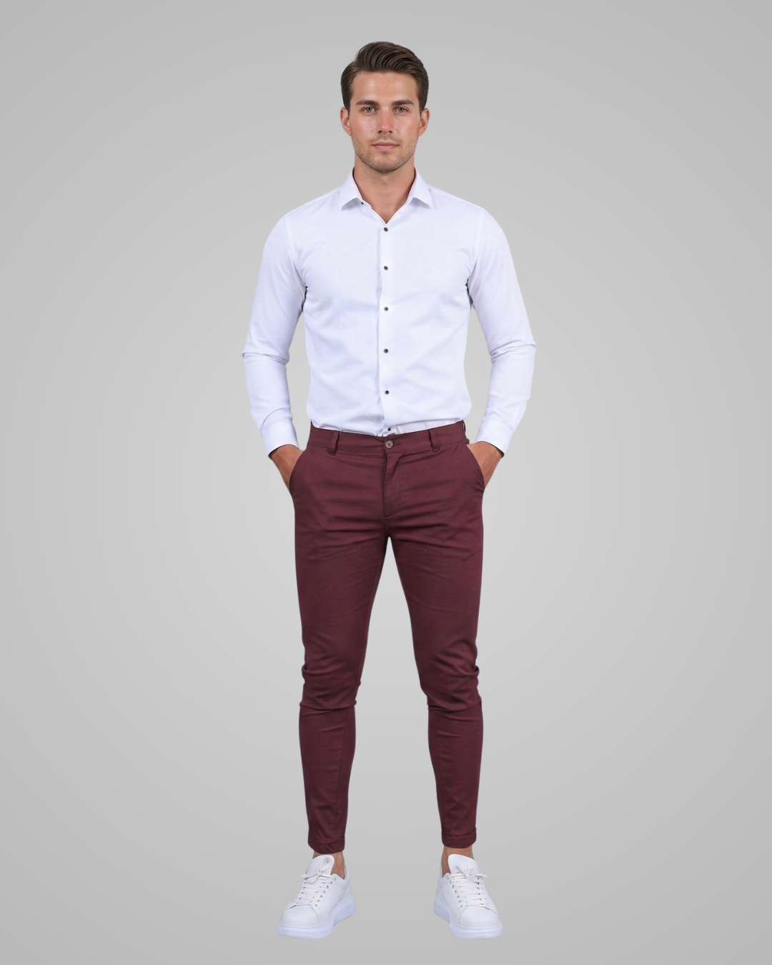 Man wearing a white shirt and maroon pants on a gray background