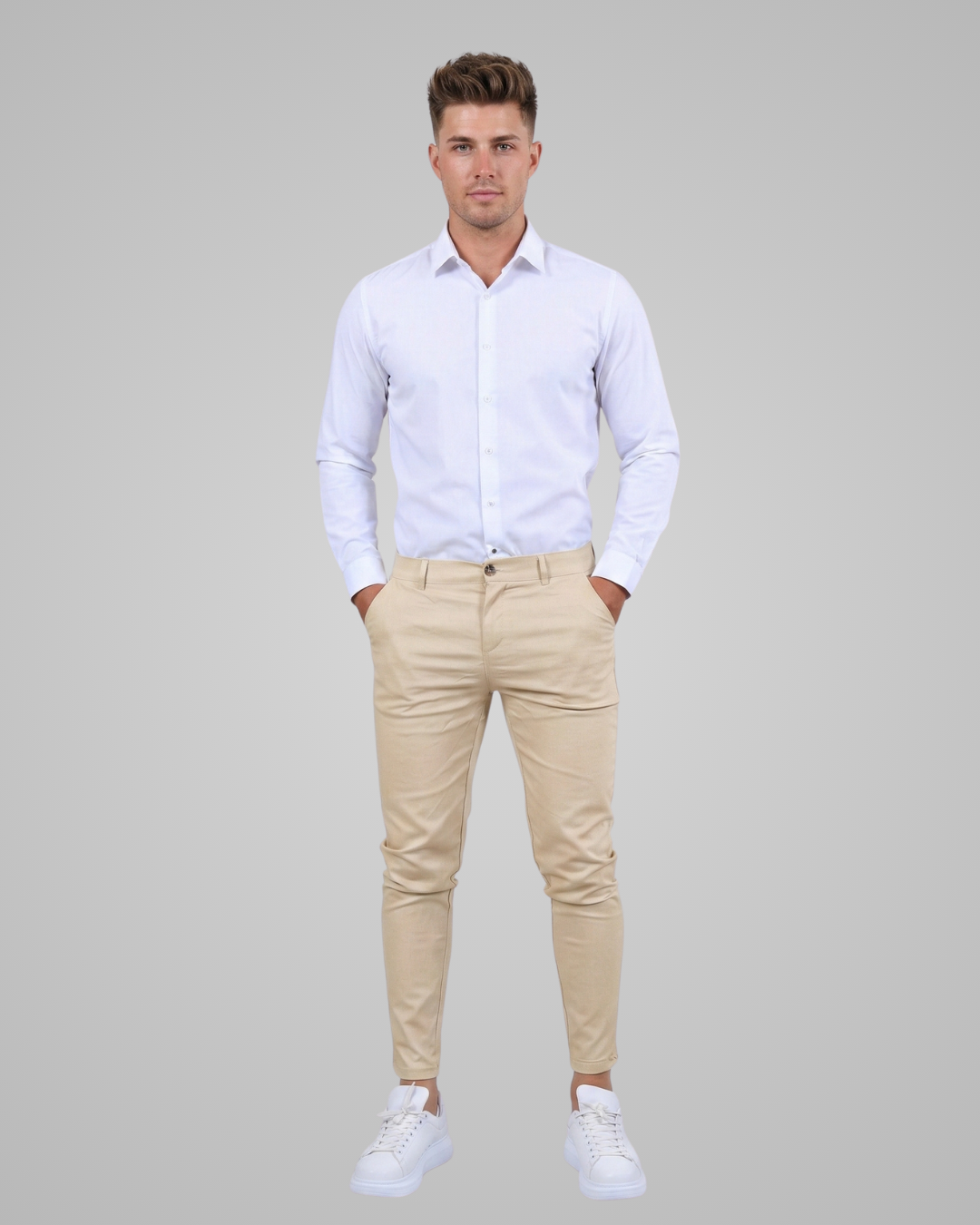 Man wearing a white shirt and beige pants on a gray background