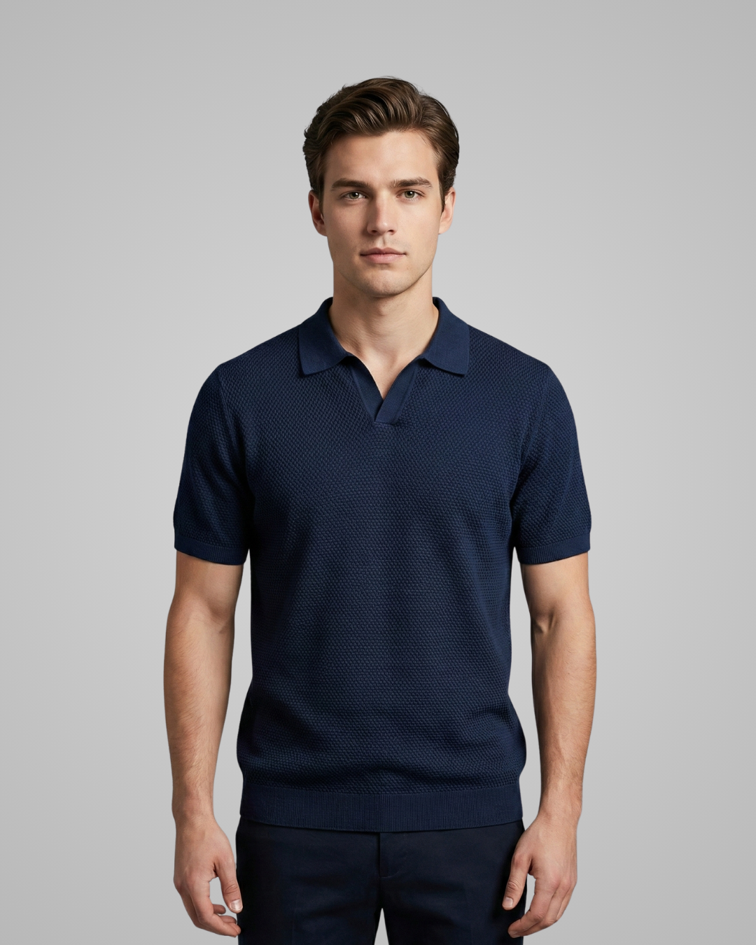 Man wearing a navy blue polo shirt against a gray background