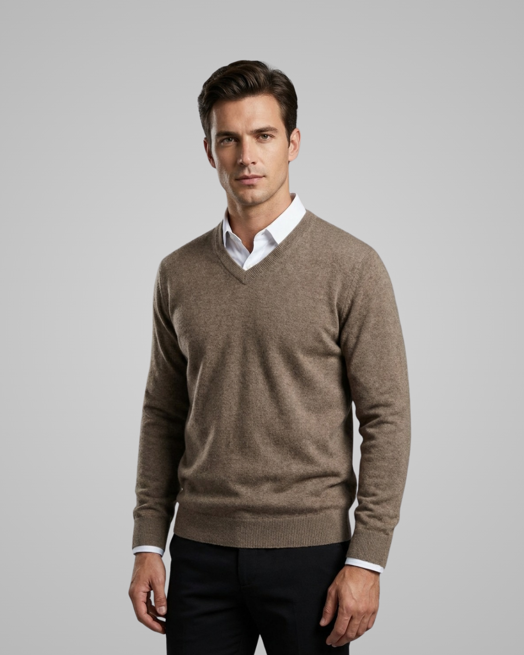 Man wearing a brown sweater over a white shirt on a gray background