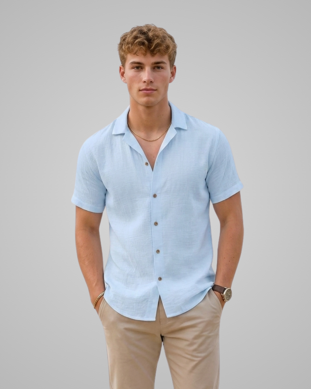 Man wearing a light blue short-sleeve shirt and beige pants against a plain background