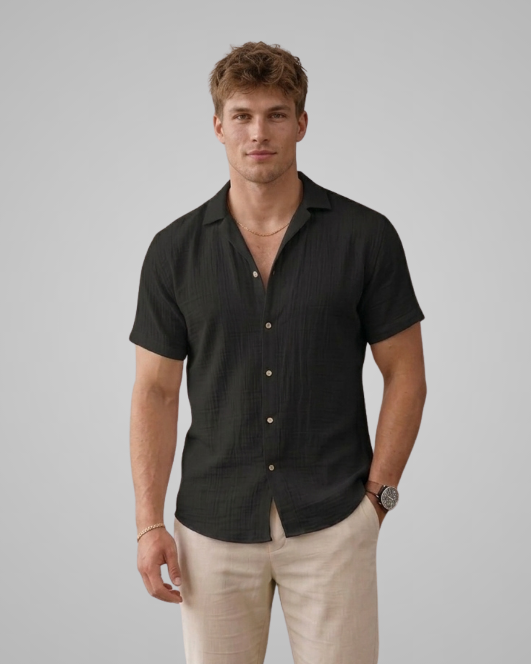 Man wearing a black short-sleeve shirt and beige pants against a gray background