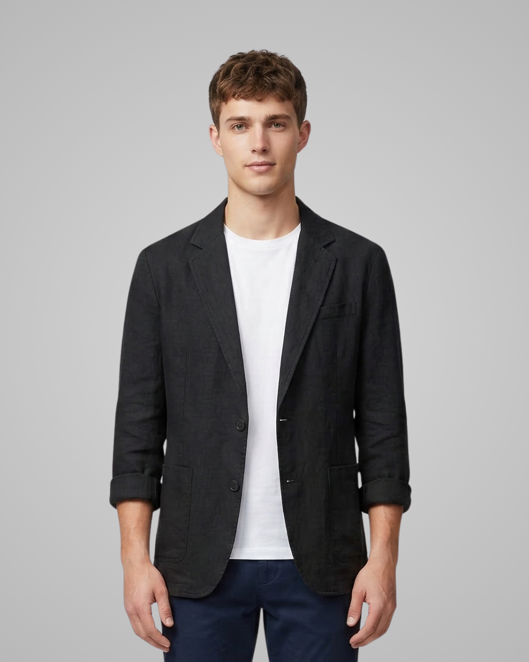 Man wearing a black blazer over a white shirt on a gray background