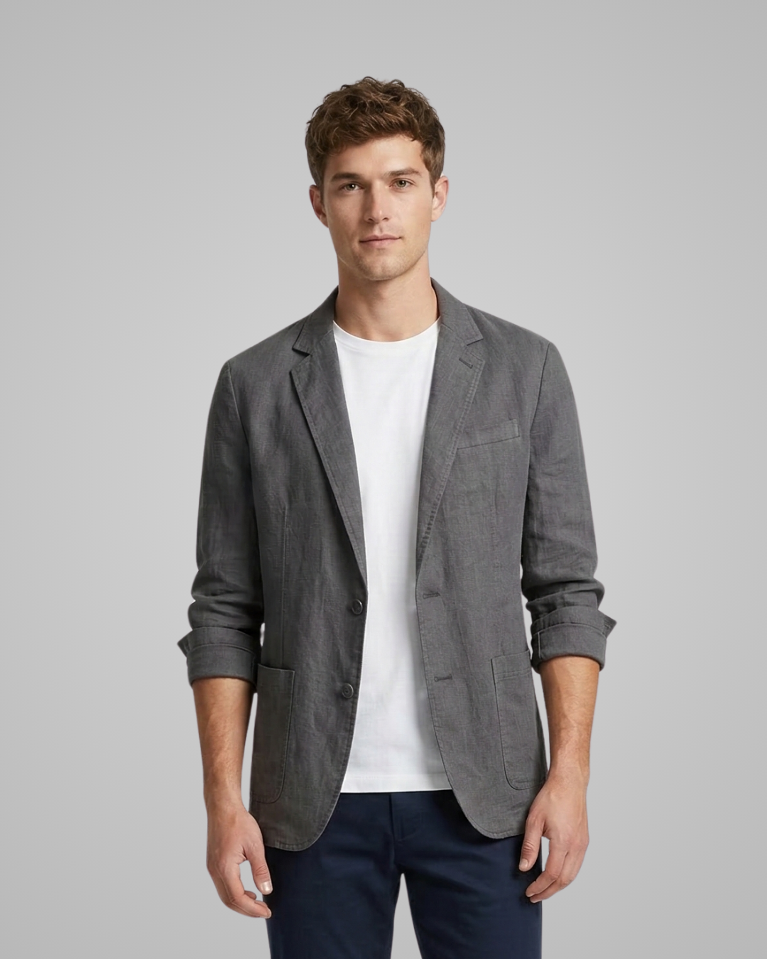 Man wearing a gray blazer over a white shirt on a gray background