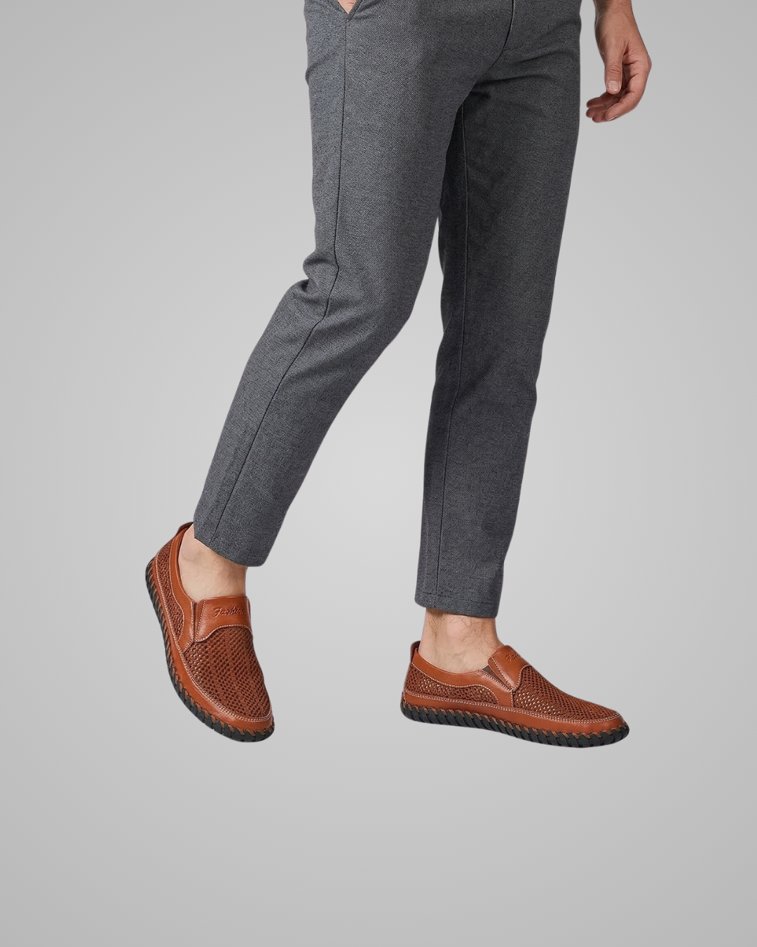 Person wearing brown loafers and gray pants on a plain background