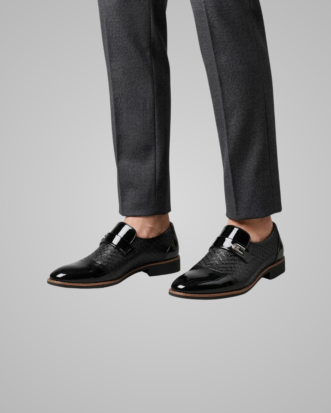 Black dress shoes worn with gray pants on a light gray background