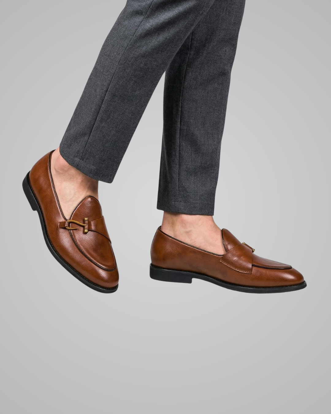 Brown loafers worn with gray pants on a gray background