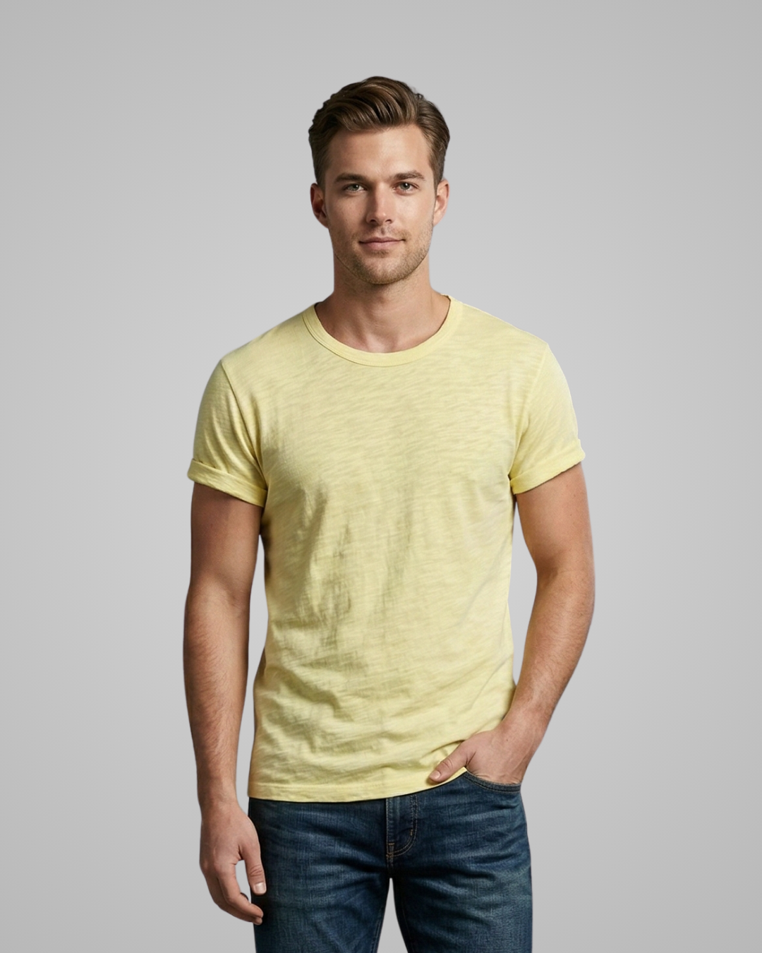 Man wearing a yellow t-shirt and blue jeans against a gray background