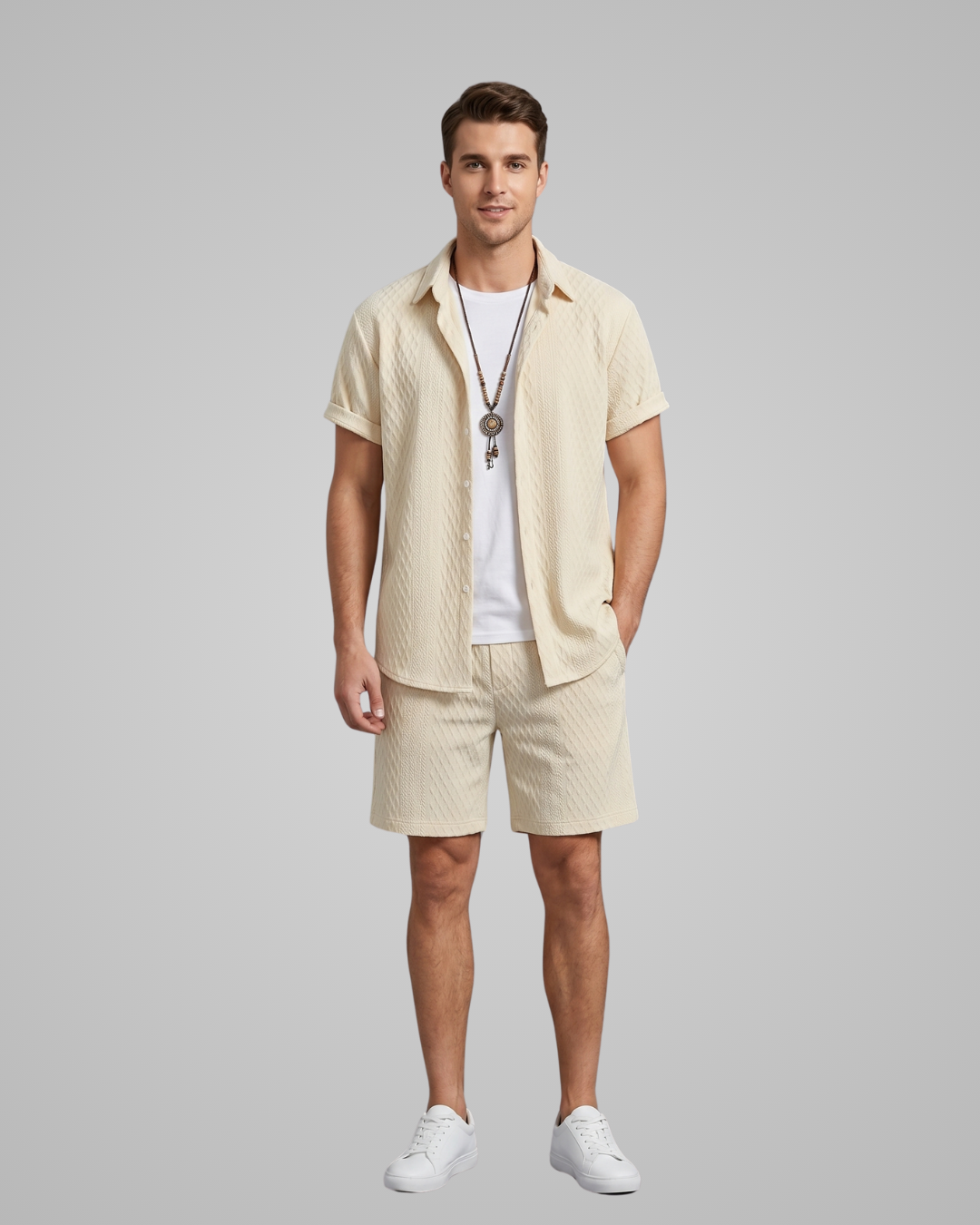 Man wearing a beige shirt and shorts set with a white t-shirt underneath on a gray background