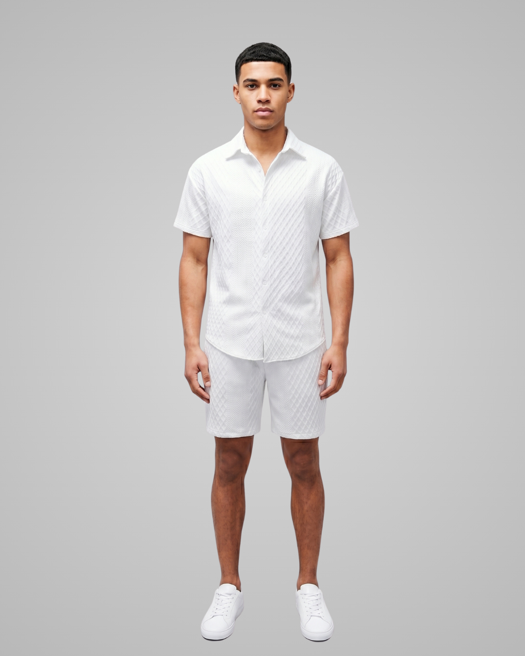 Man wearing a white patterned shirt and shorts on a gray background