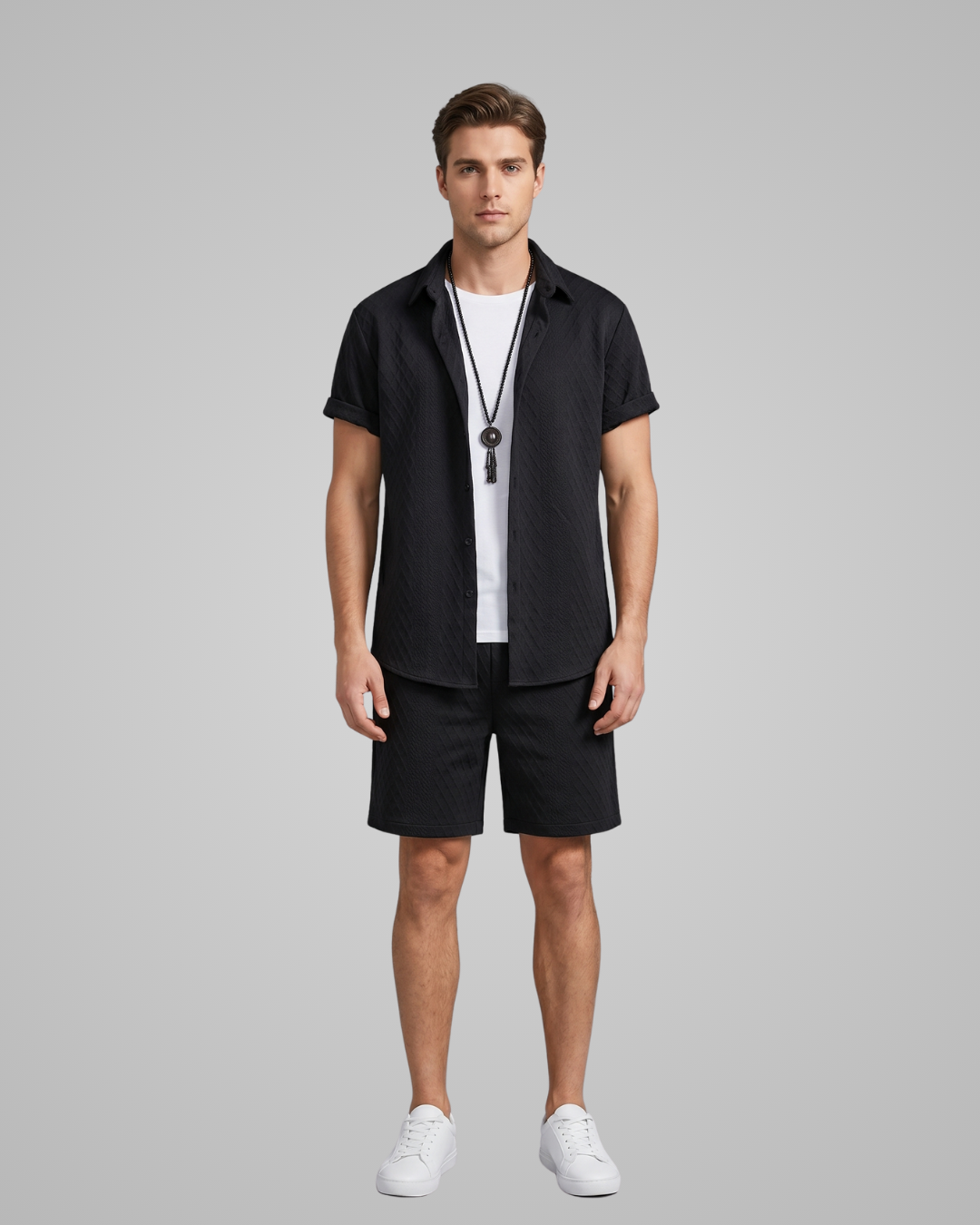 Man wearing a black shirt and shorts with a white t-shirt underneath on a gray background
