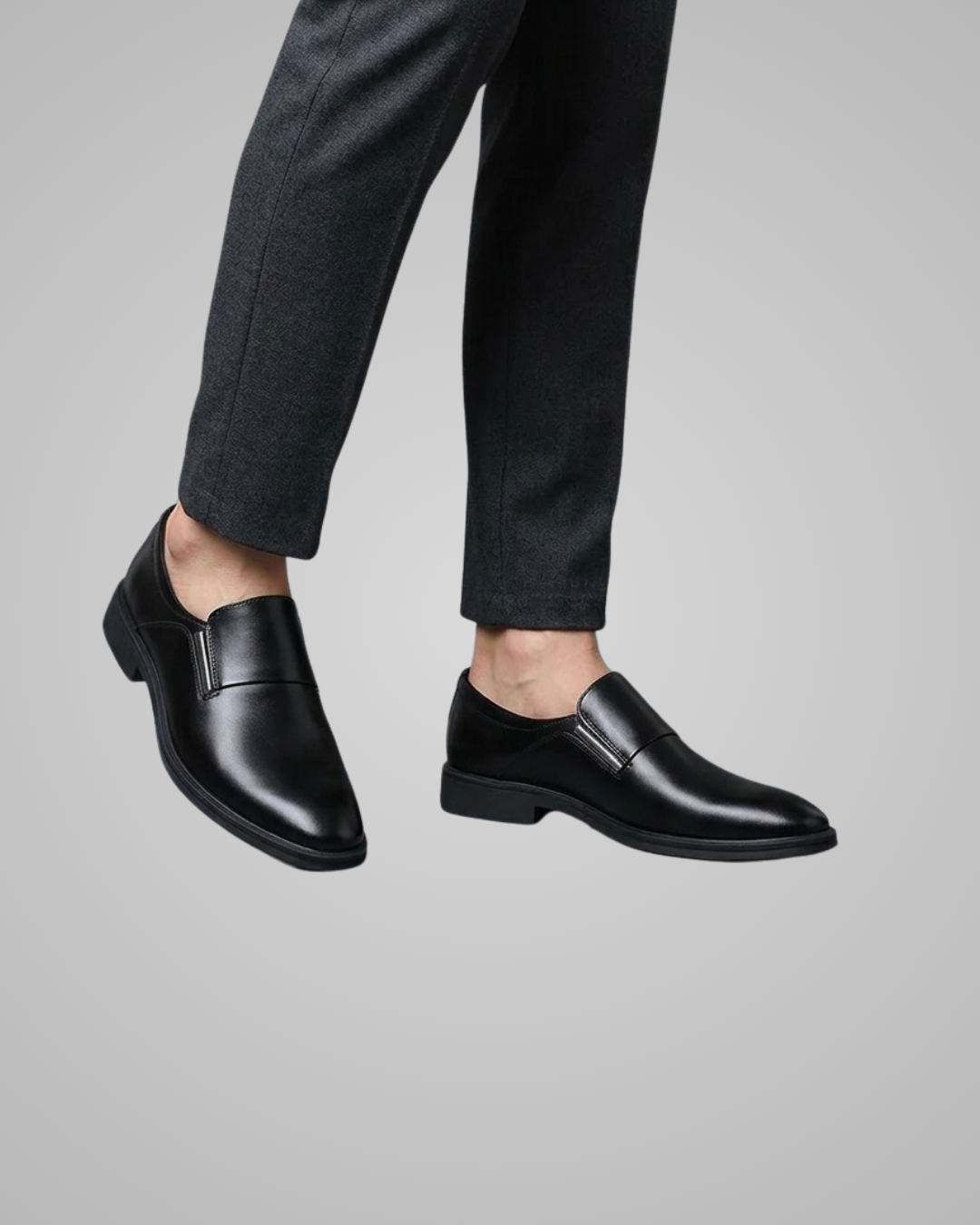 Black dress shoes worn with dark pants on a gray background