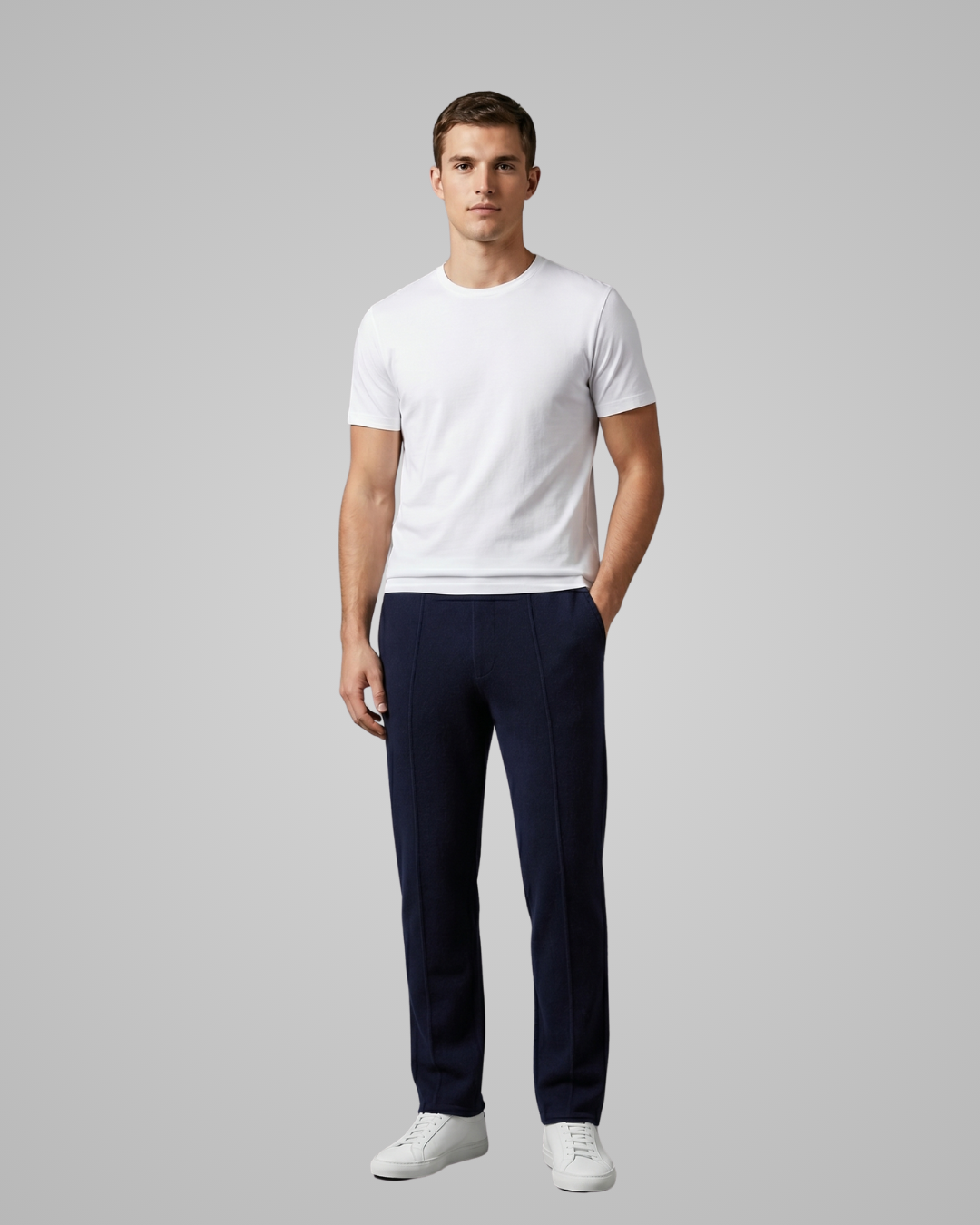 Man wearing a white t-shirt and navy pants on a gray background