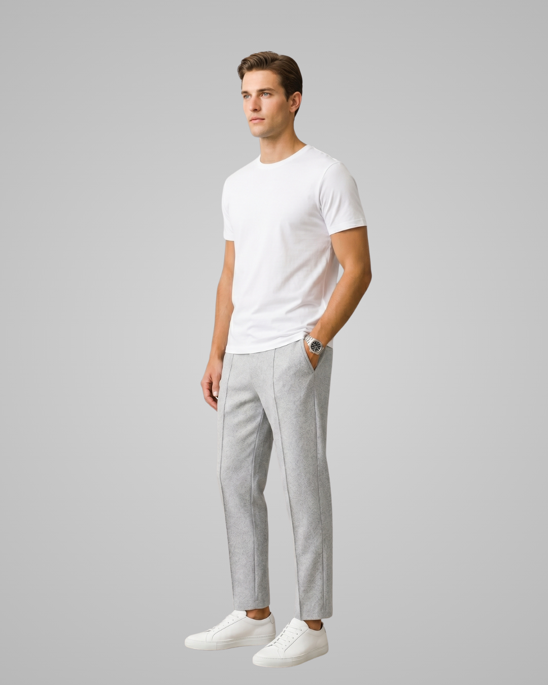 Man wearing a white t-shirt and gray pants on a plain background