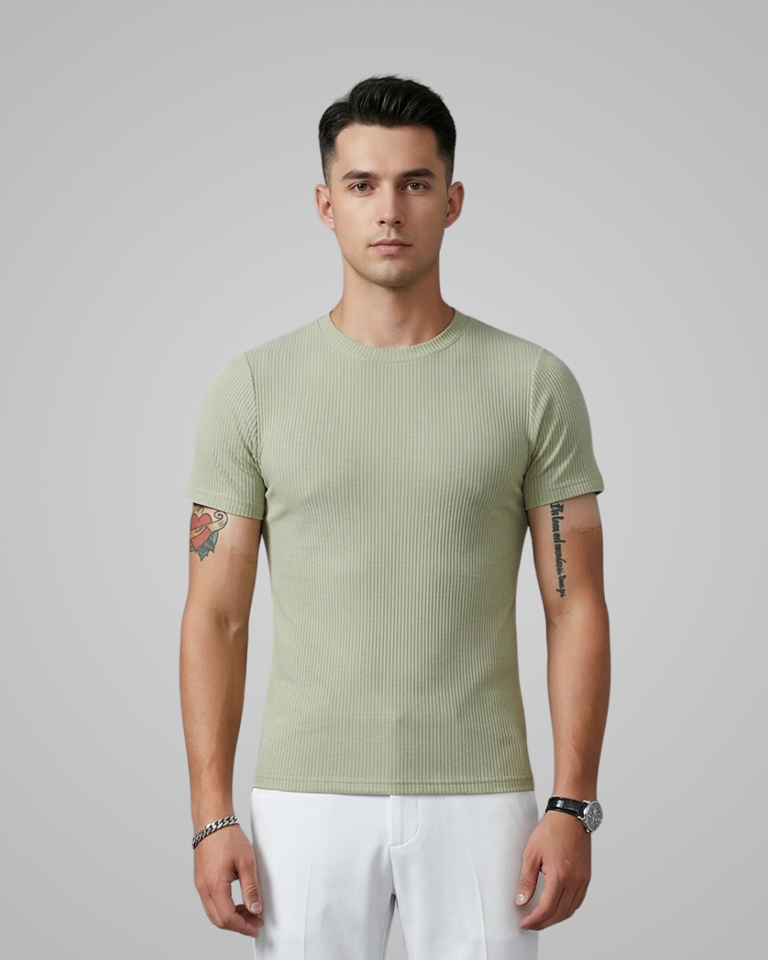 Man wearing a light green ribbed t-shirt and white pants against a gray background