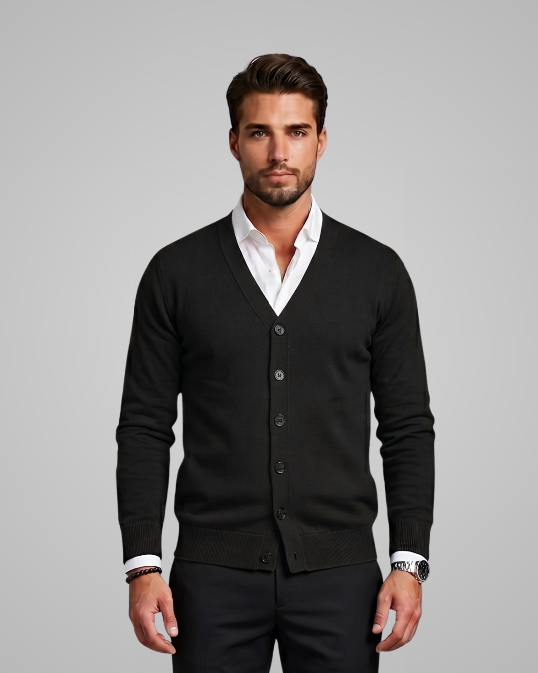 Man wearing a black cardigan over a white shirt on a gray background