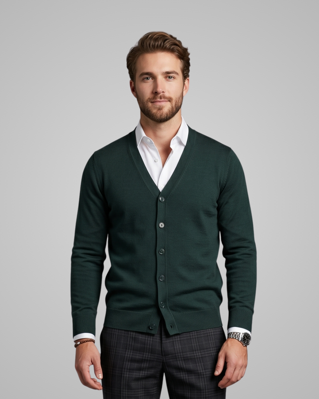 Man wearing a green cardigan over a white shirt with a gray background