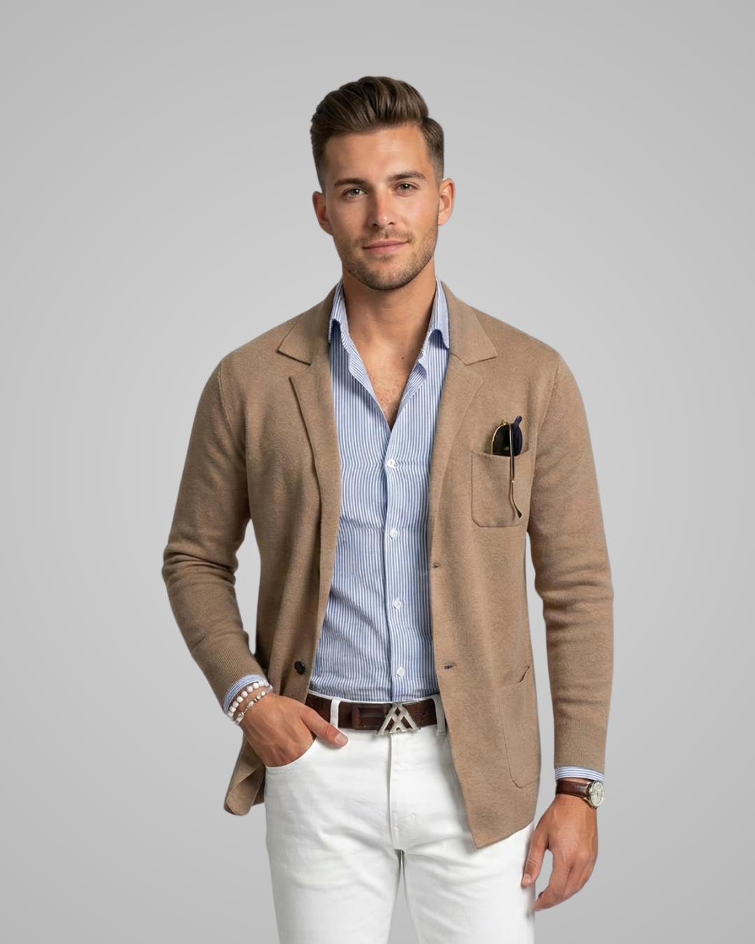 Man wearing a beige blazer over a striped shirt with white pants on a gray background
