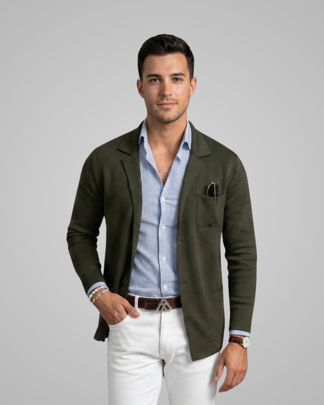 Man wearing a green blazer over a light blue shirt with white pants on a gray background