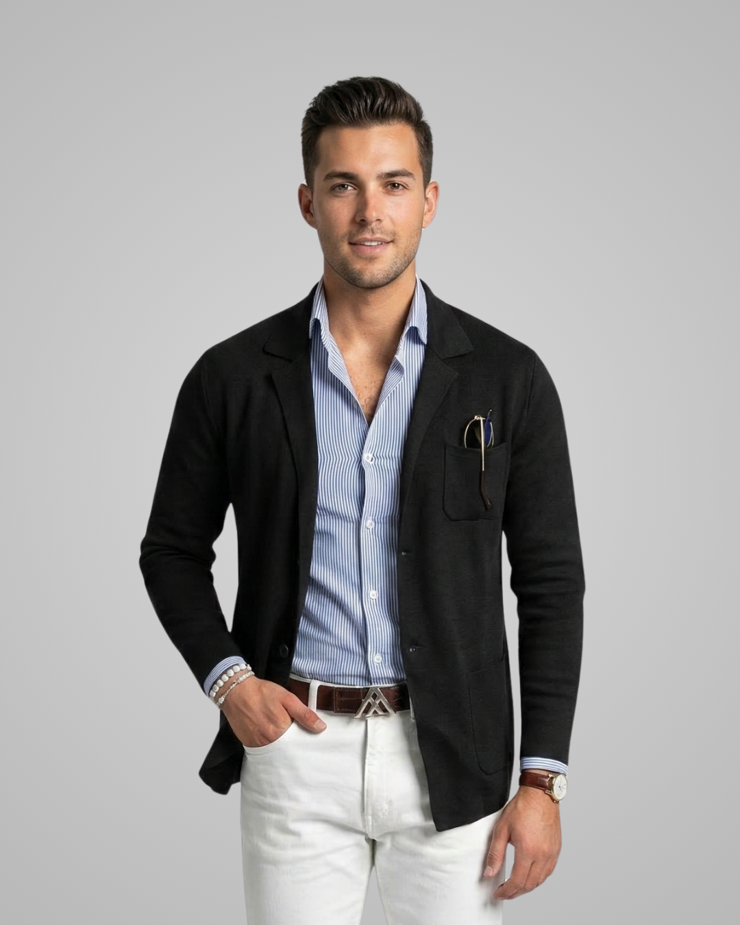 Man wearing a black jacket over a light blue shirt with white pants on a gray background