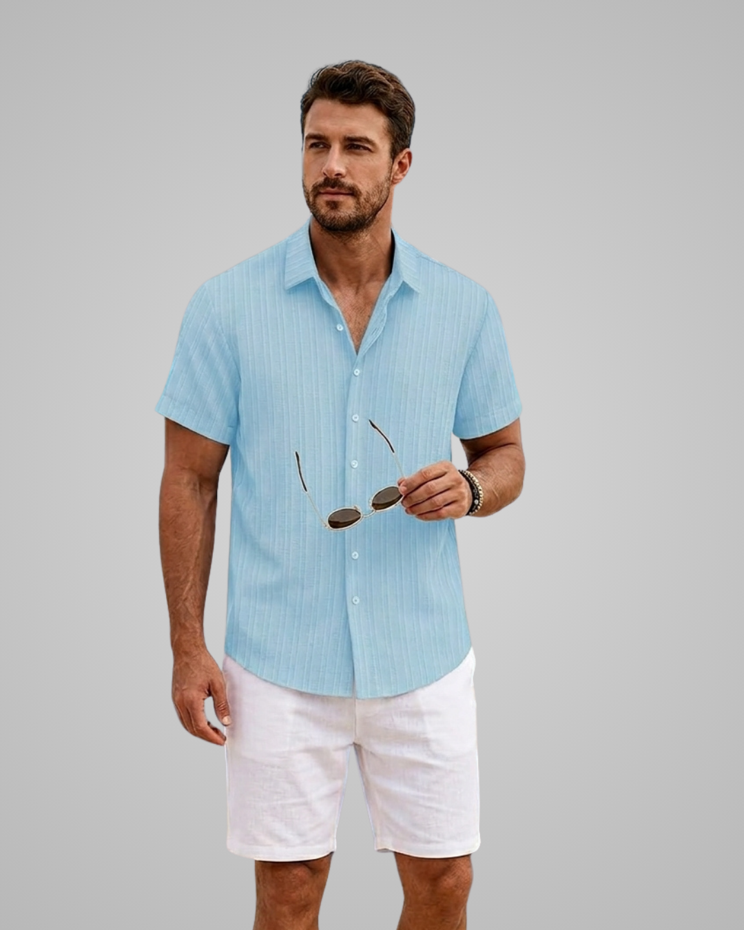 Man wearing a light blue striped shirt and white shorts against a gray background