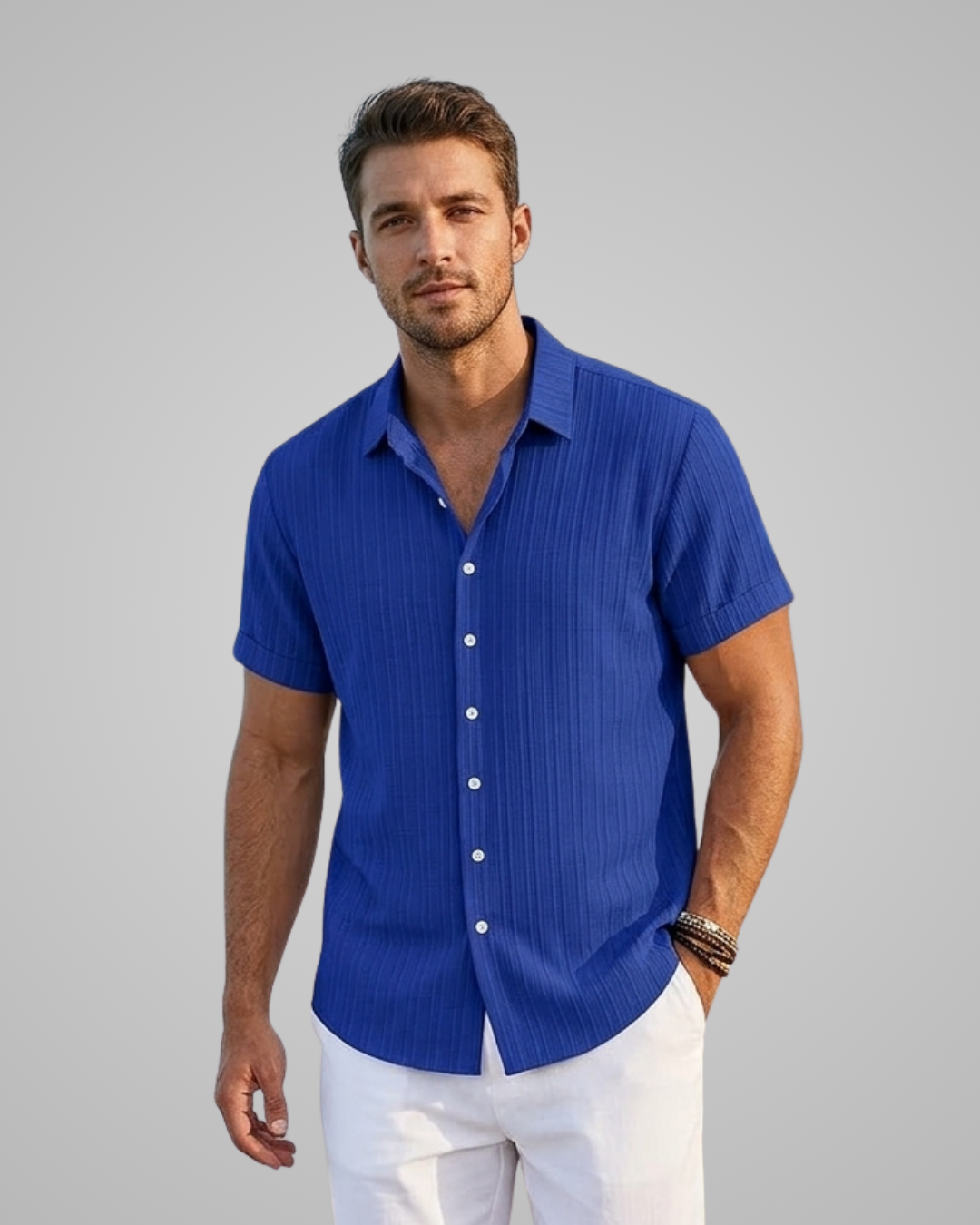 Man wearing a blue short-sleeve shirt and white pants on a gray background