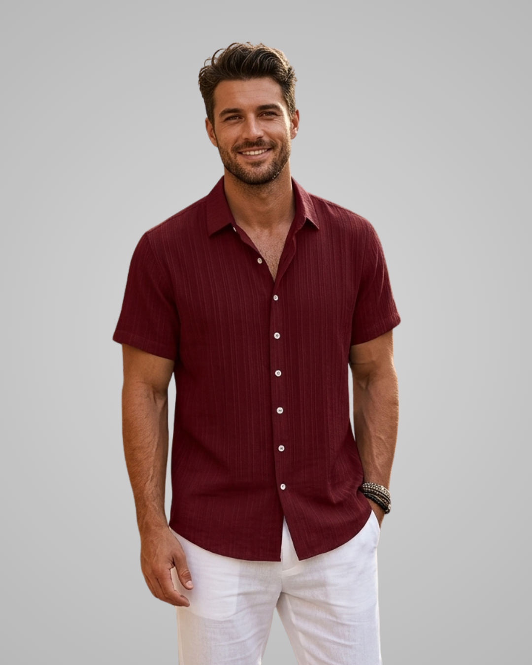Man wearing a maroon short-sleeve shirt and white pants against a gray background