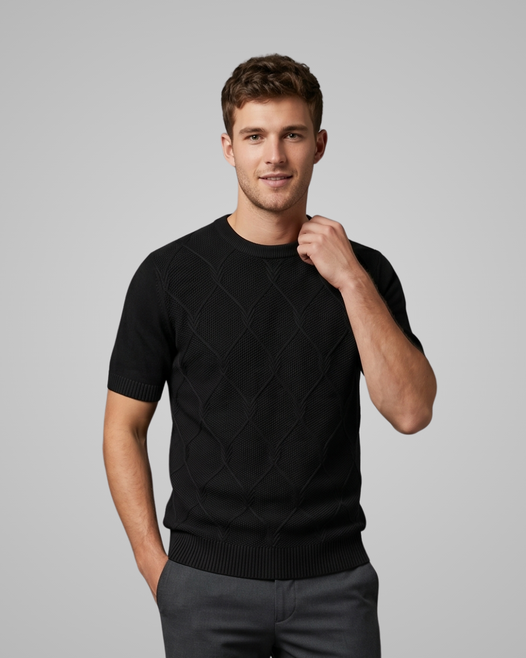 Man wearing a black short-sleeve sweater against a gray background