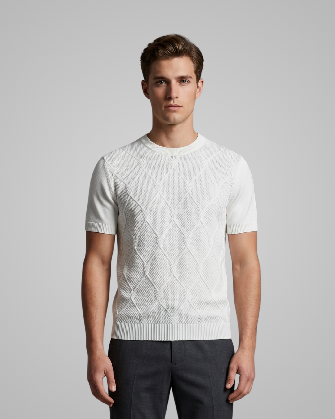 Man wearing a white patterned sweater against a gray background