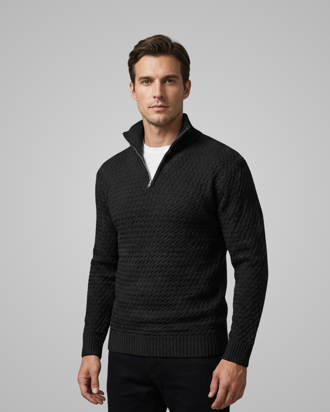 Man wearing a black cable knit sweater against a gray background
