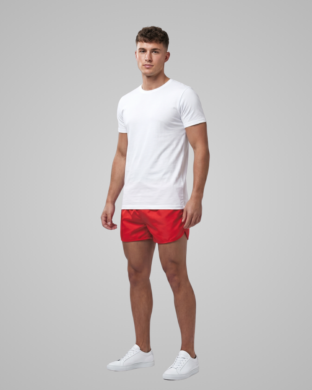 Man wearing a white t-shirt and red shorts on a gray background
