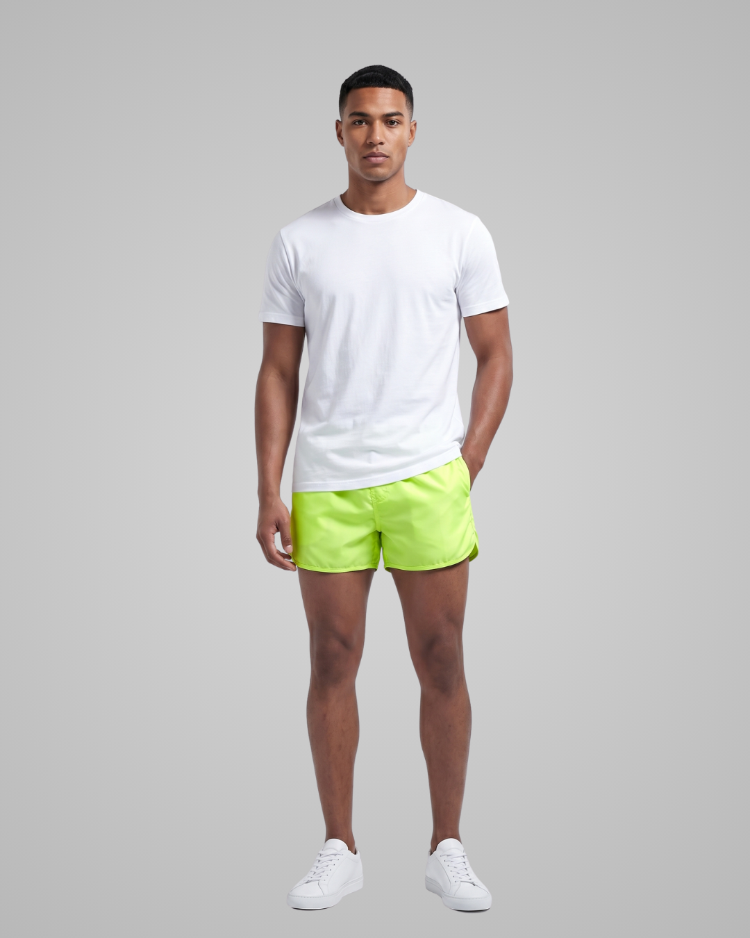 Man wearing a white t-shirt and bright green shorts on a gray background