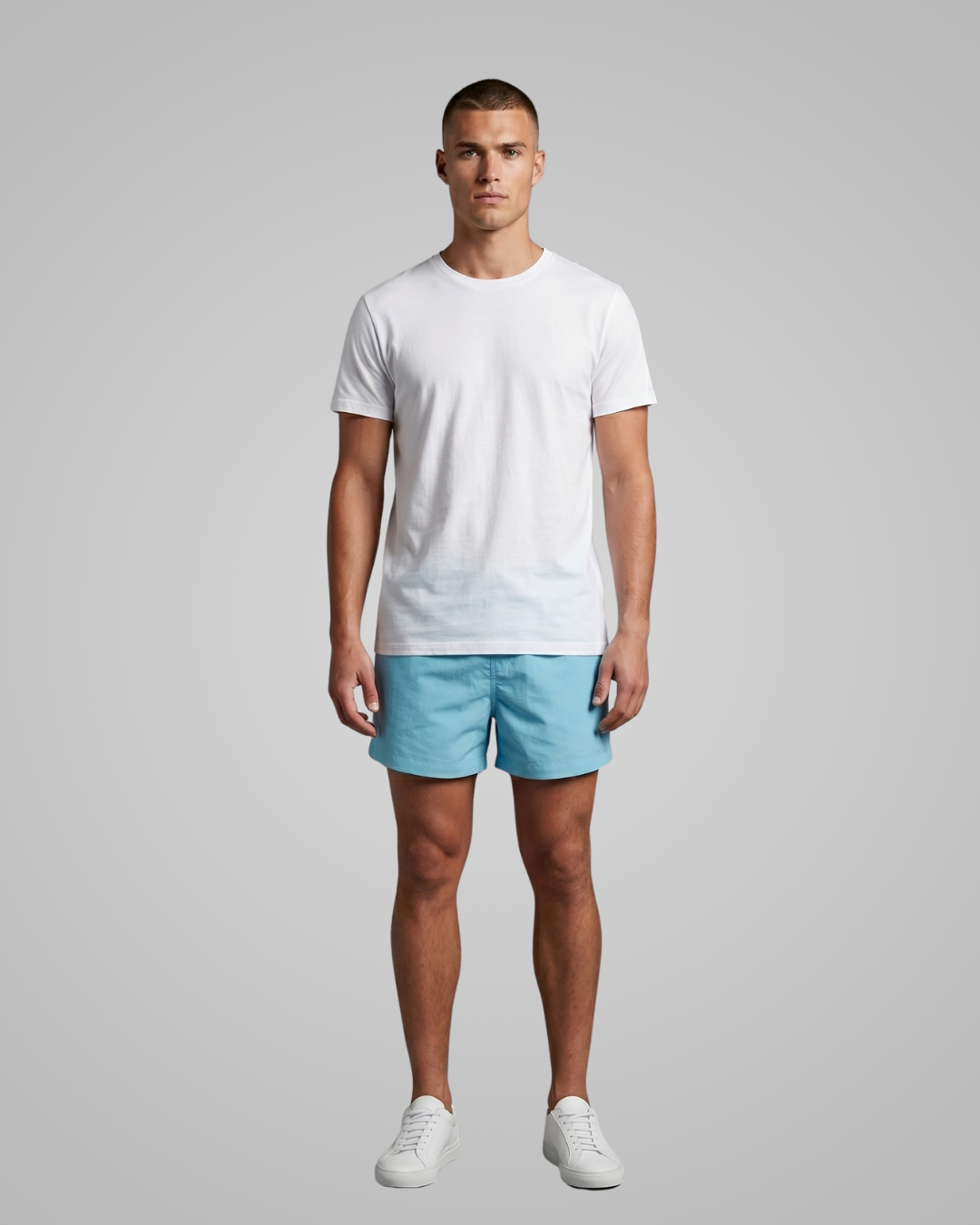 Man wearing a white t-shirt and light blue shorts on a gray background