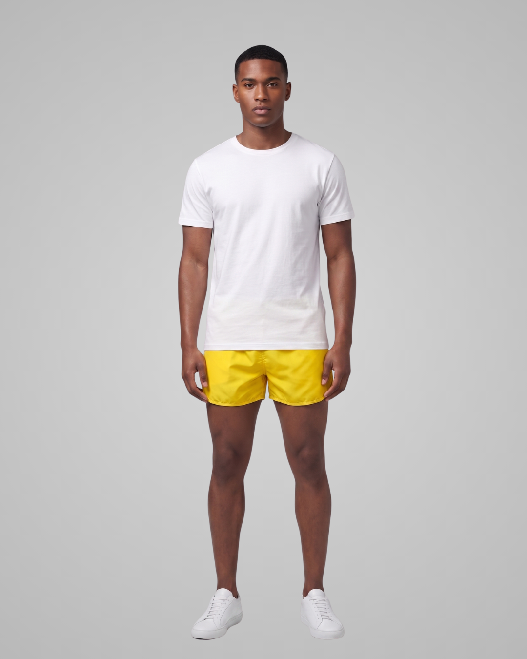 Man wearing a white t-shirt and yellow shorts on a gray background