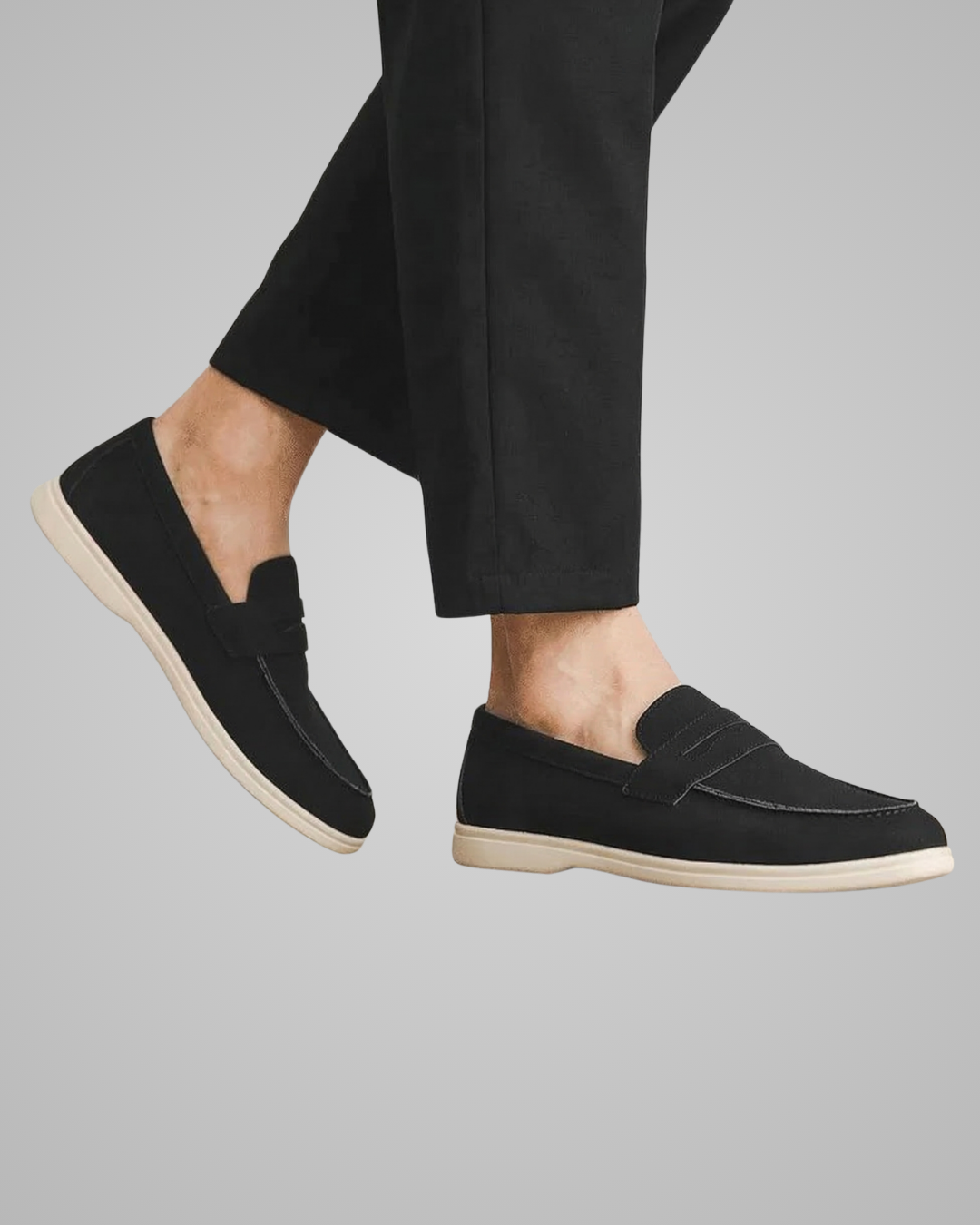 Black loafers worn with black pants on a gray background