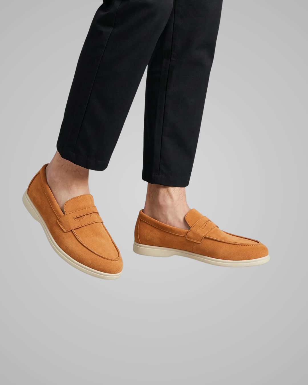 Brown loafers worn with black pants on a gray background