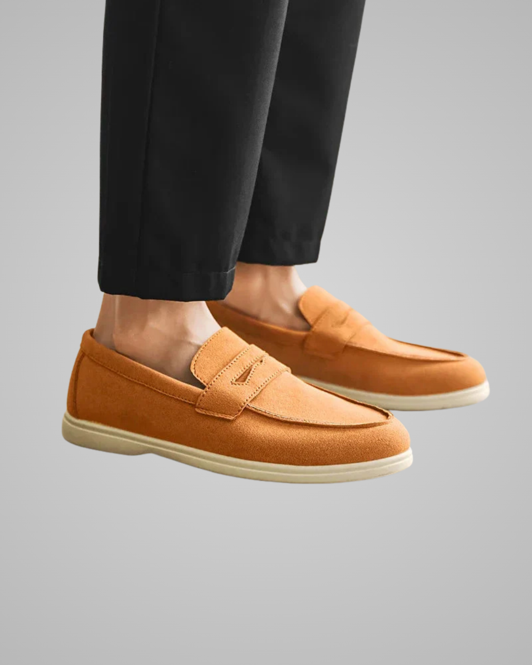 Brown loafers worn with black pants on a gray background