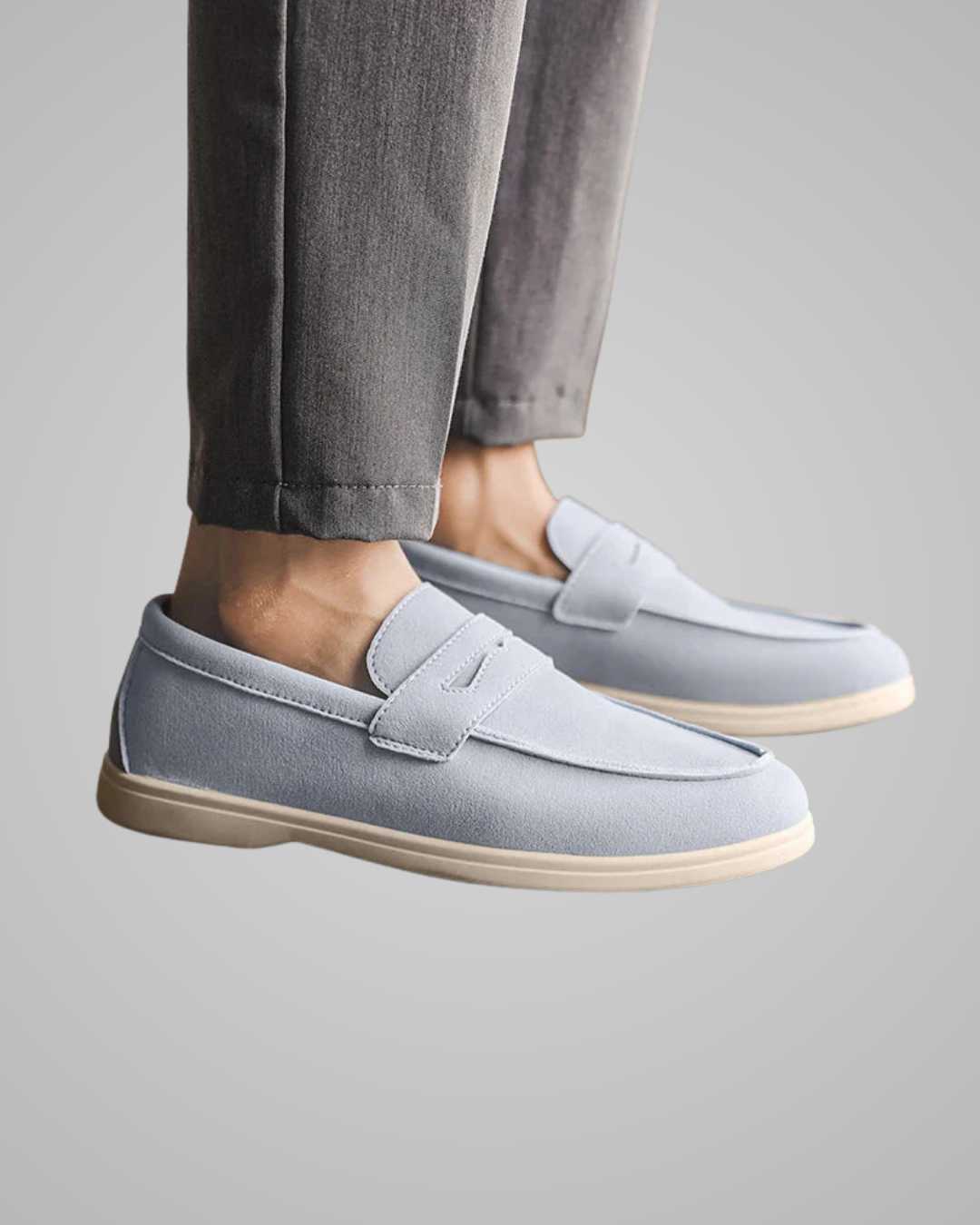 Light gray loafers worn with gray pants on a neutral background