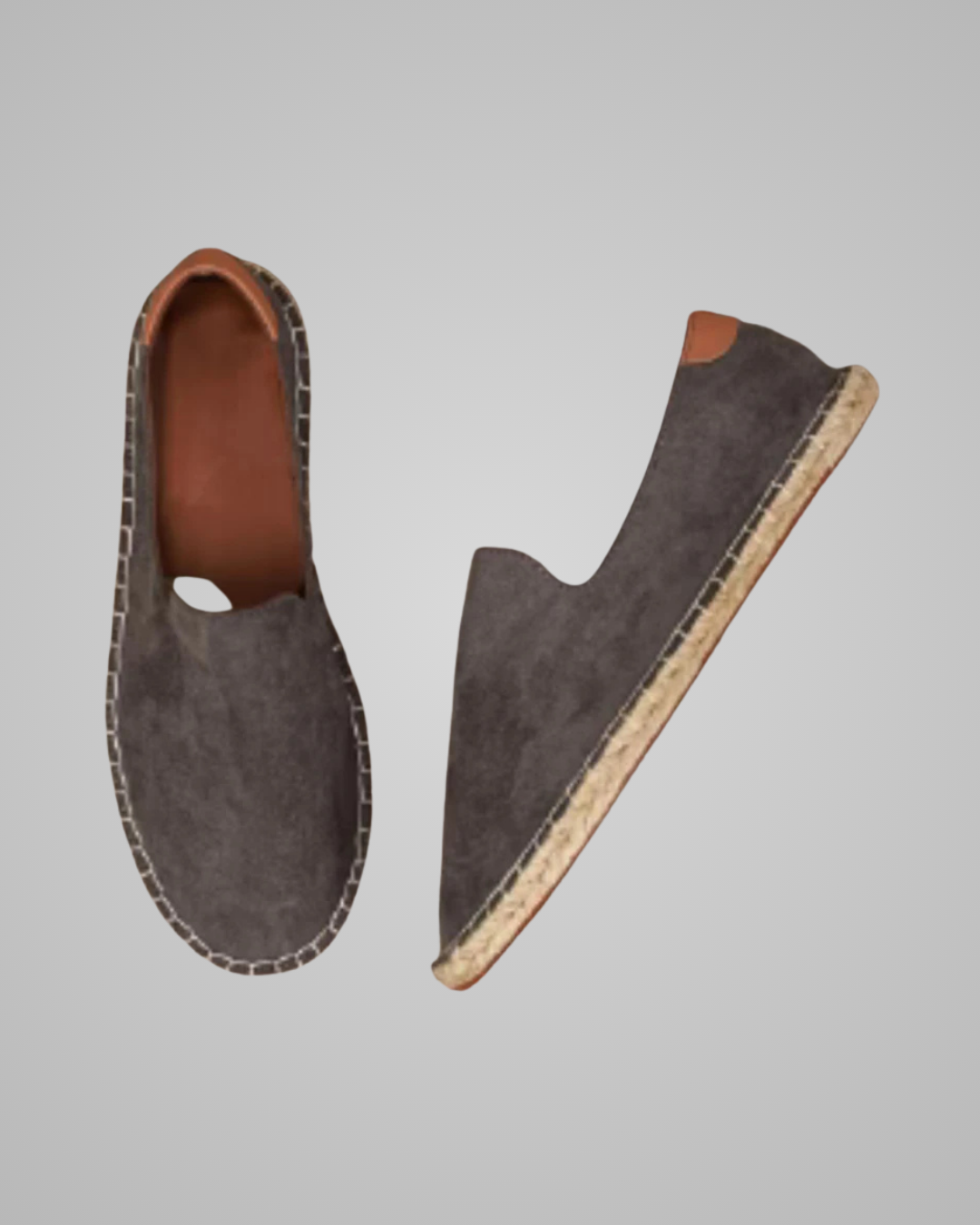 A pair of dark gray suede slip-on espadrille-style shoes shown from top and side angles against a solid gray background.