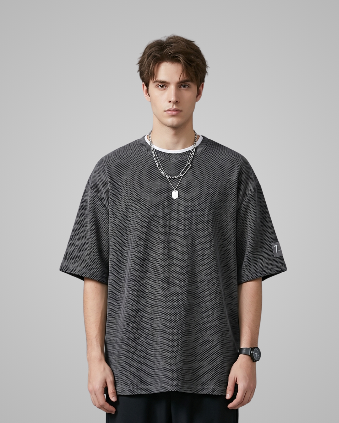 Man wearing a dark gray textured t-shirt on a gray background