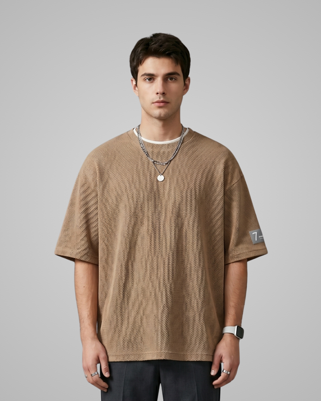 Man wearing a brown textured t-shirt on a gray background